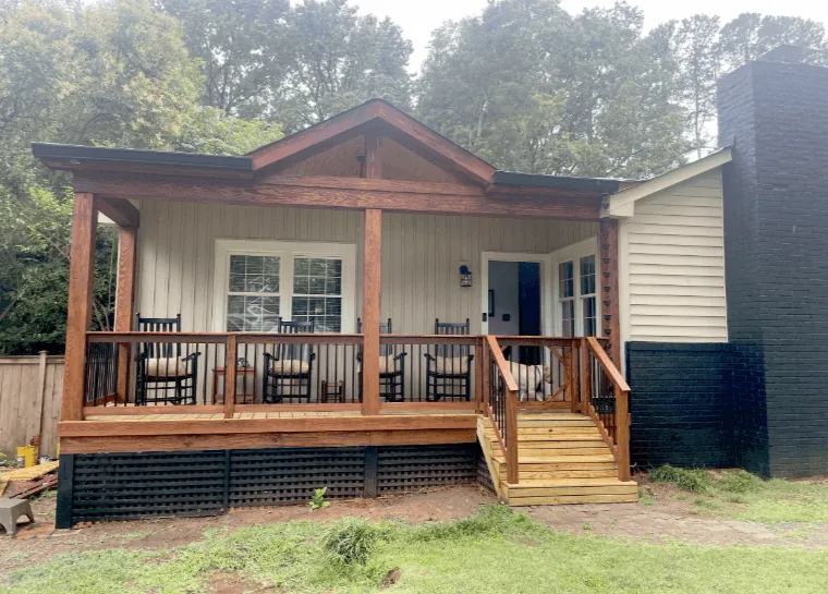 Covered front porch with a timber-framed gable, wood railing and a row of rocking chairs