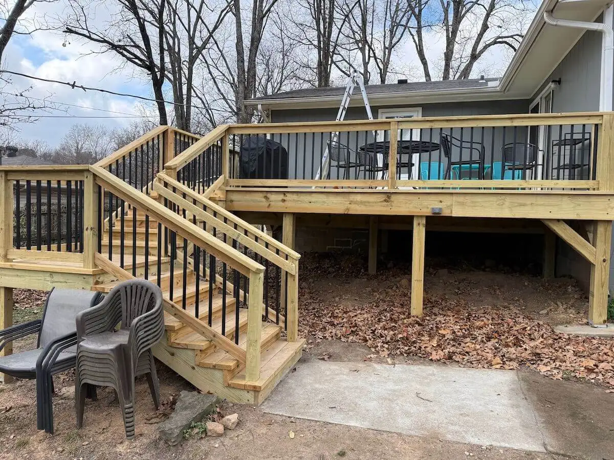 Elevated pressure-treated wood deck with black balusters and a full staircase to the back yard