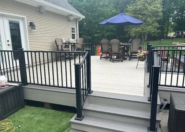 Gray composite deck with black aluminum railing, wide steps and an outdoor seating area