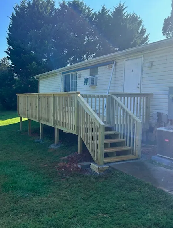 Southern yellow pine deck with matching railing and a short staircase at the rear of a home