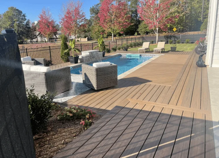 Two-tone composite pool deck in brown and charcoal with a picture-frame border and poolside lounge furniture